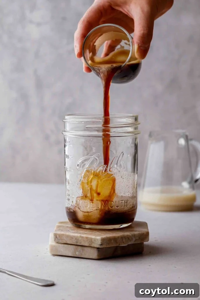 Brown Sugar Oat Espresso Velvet 8 Pouring espresso over ice in a jar