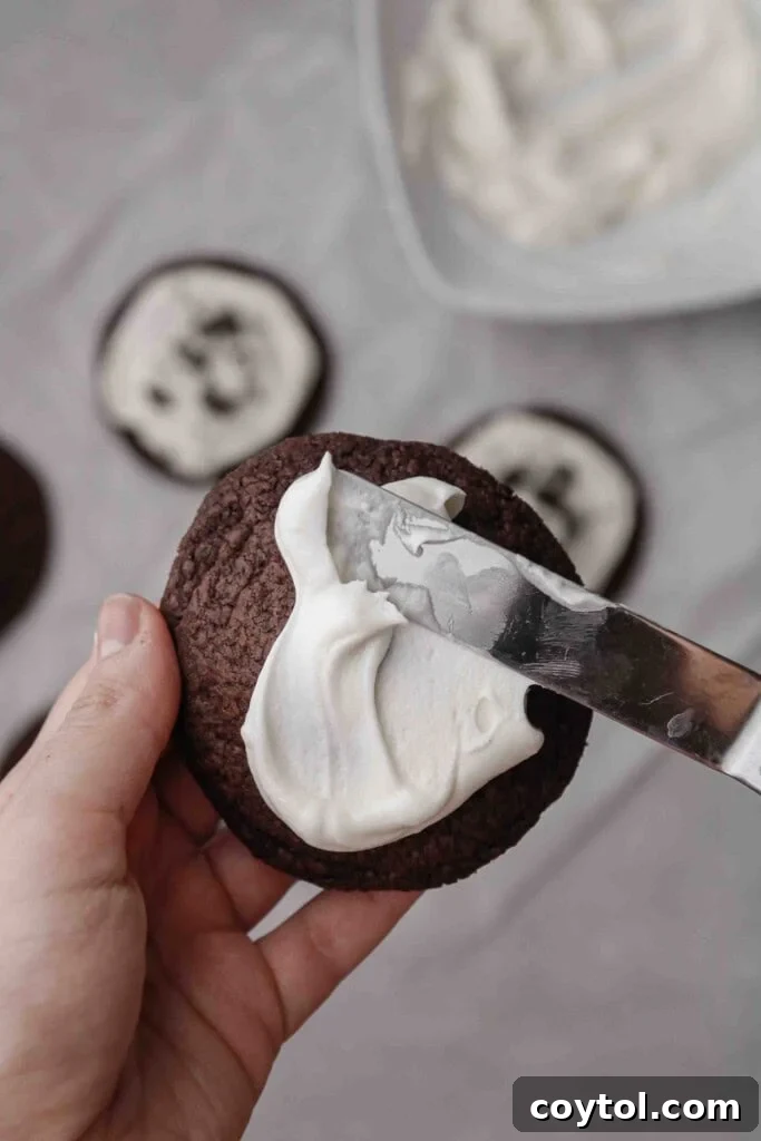 Homemade Crumbl Oreo Buttercream Cookies 13 Applying buttercream frosting to a chocolate Oreo cookie