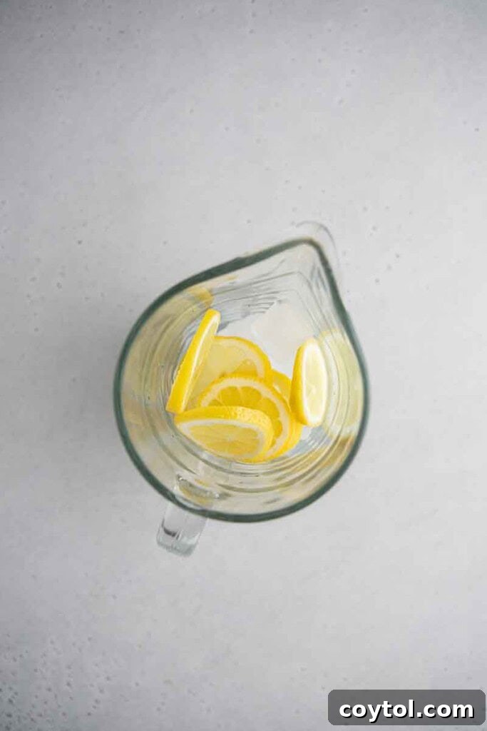 Thinly sliced lemon and ice cubes in a pitcher for making creamy lemonade