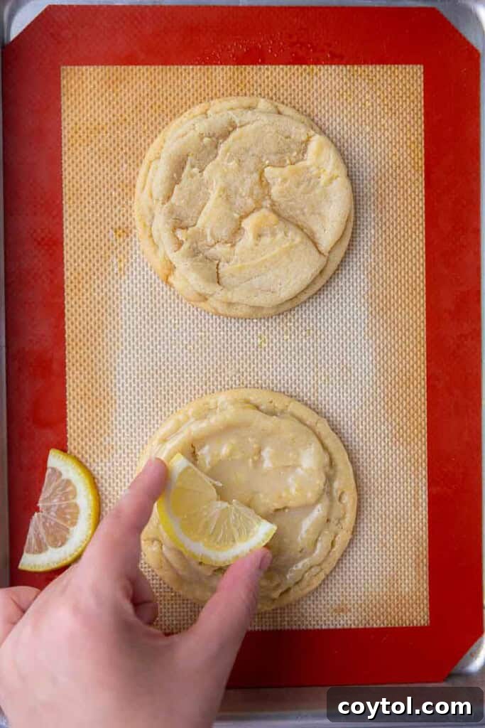Effortless Bakery-Style Lemon Glaze Cookies 13 Hand placing a lemon slice on a glazed cookie