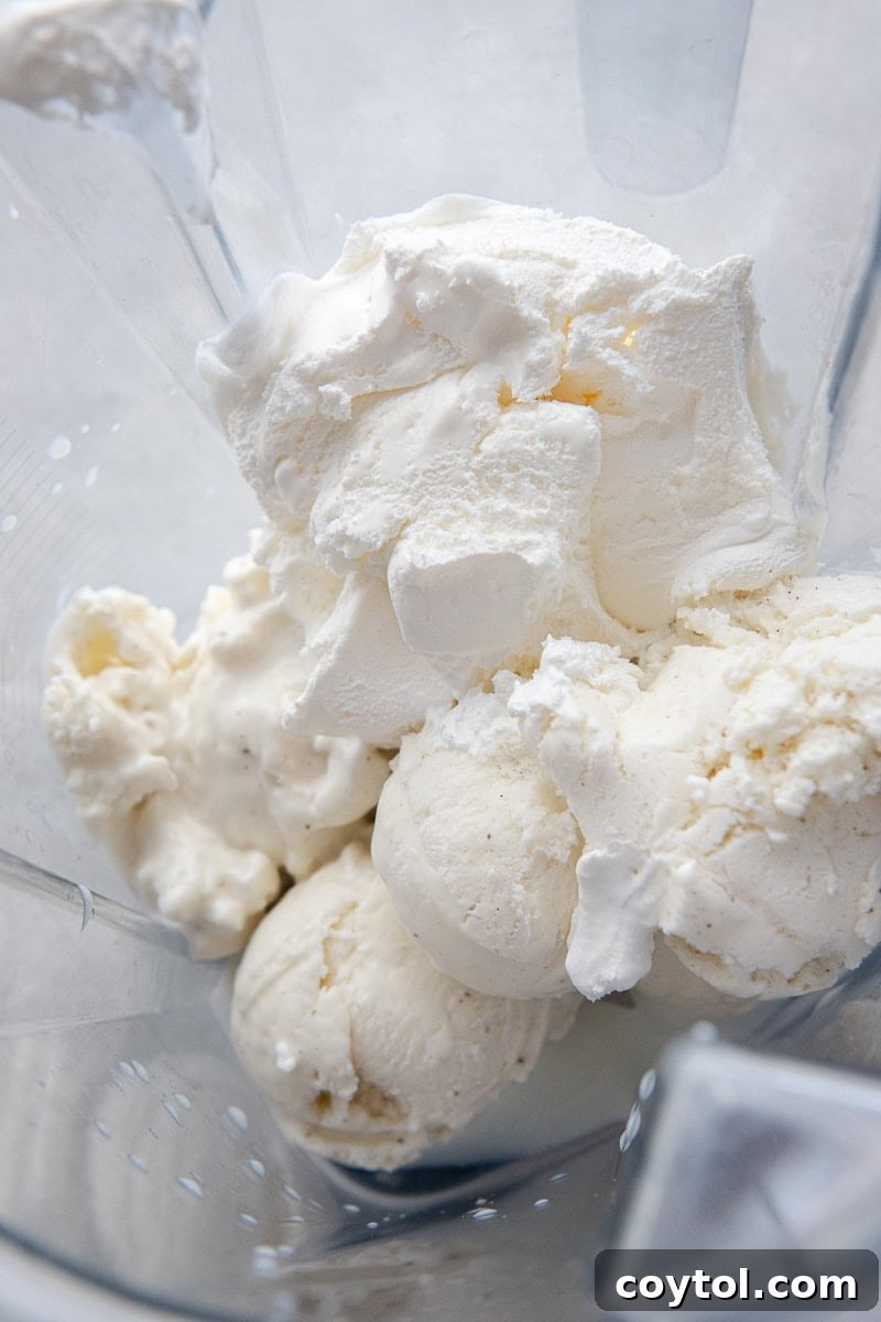 Vanilla ice cream and cool whip being blended in a cup.