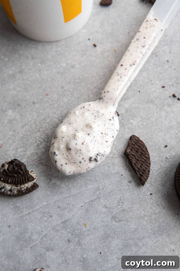 A spoonful of creamy Oreo McFlurry, showing the soft serve texture and crushed cookie pieces.