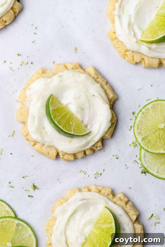 Zesty Island Chill Coconut Lime Cookies 15 Overhead shot of freshly frosted CRUMBL lime cookies with lime wedges.