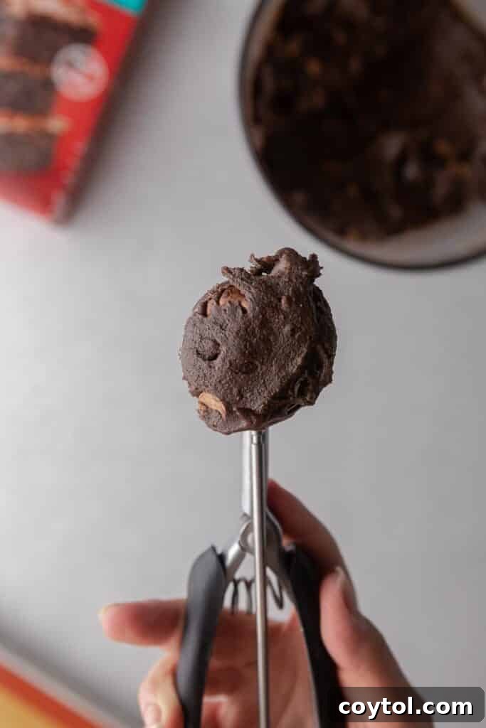 Decadent Crumbl Brownie Batter Cookies 10 A cookie scooper portioning out cookie dough.