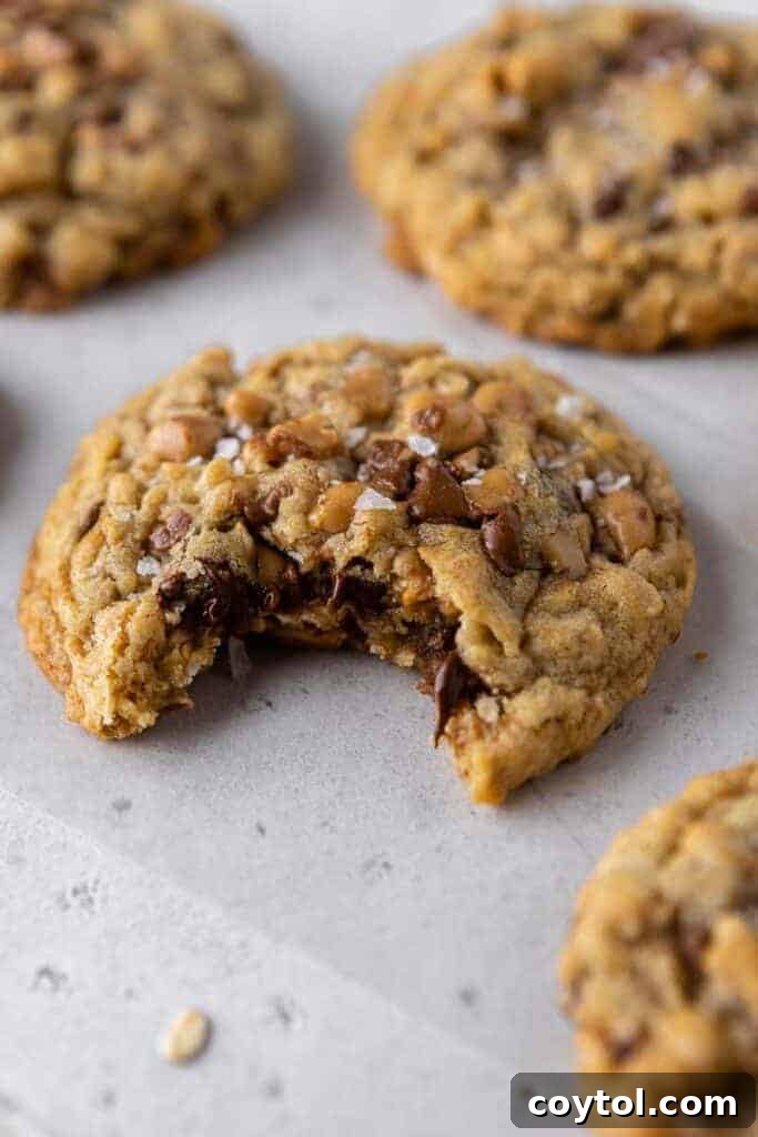 Crumbl Mom's Recipe Cookie with a bite taken out, showing its soft interior and mix-ins.