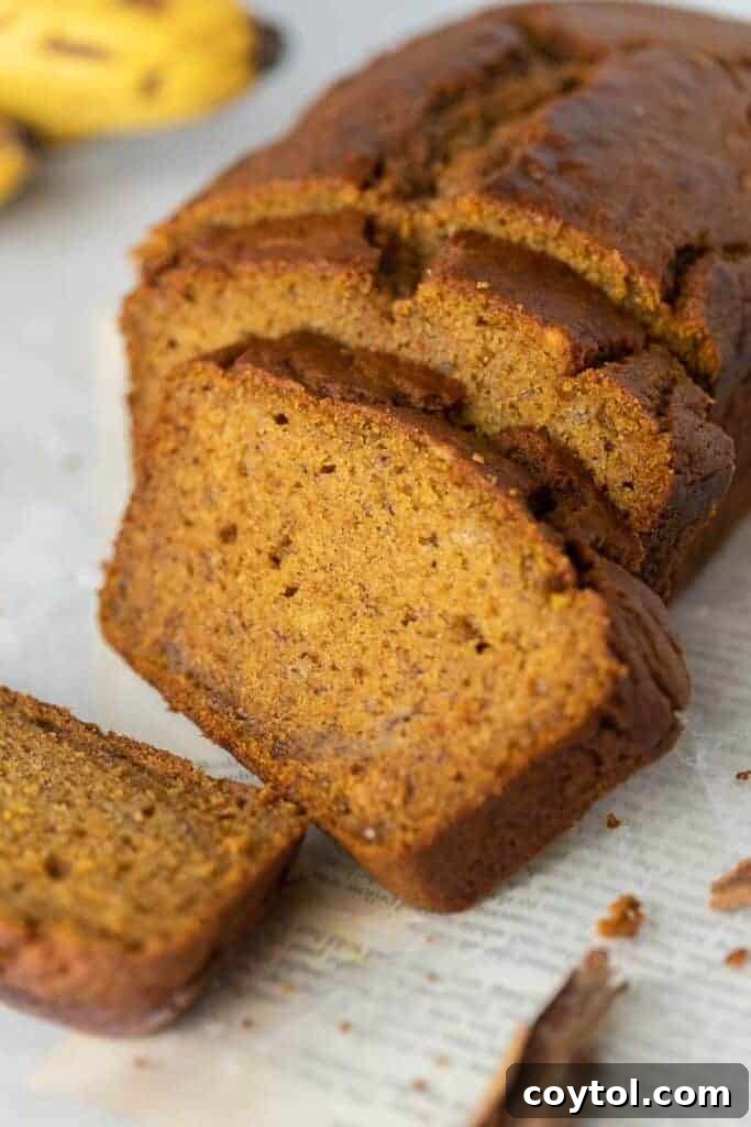 Freshly baked golden-brown pumpkin banana bread loaf on a wooden cutting board, ready for slicing.
