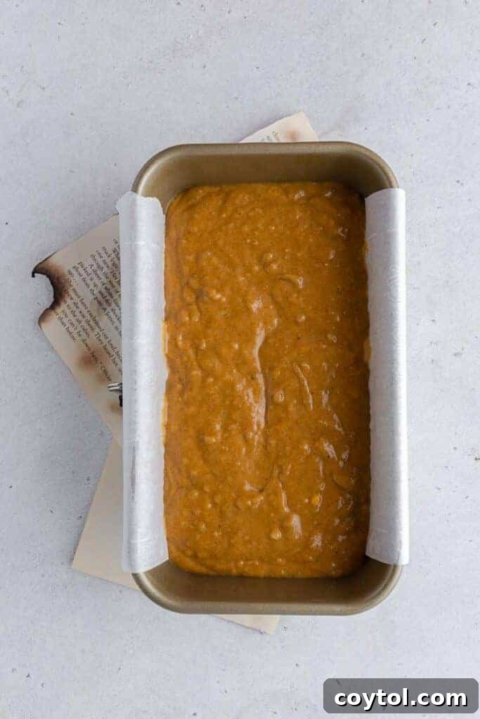 Pumpkin banana bread batter poured into a parchment-lined loaf pan, ready for baking.