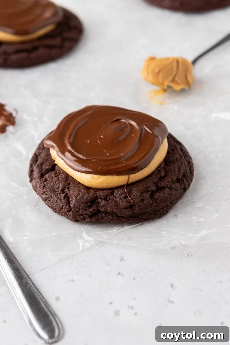 Rich Crumbl-style Buckeye Brownie Cookies, featuring fudgy brownie, creamy peanut butter fudge, and melted chocolate.
