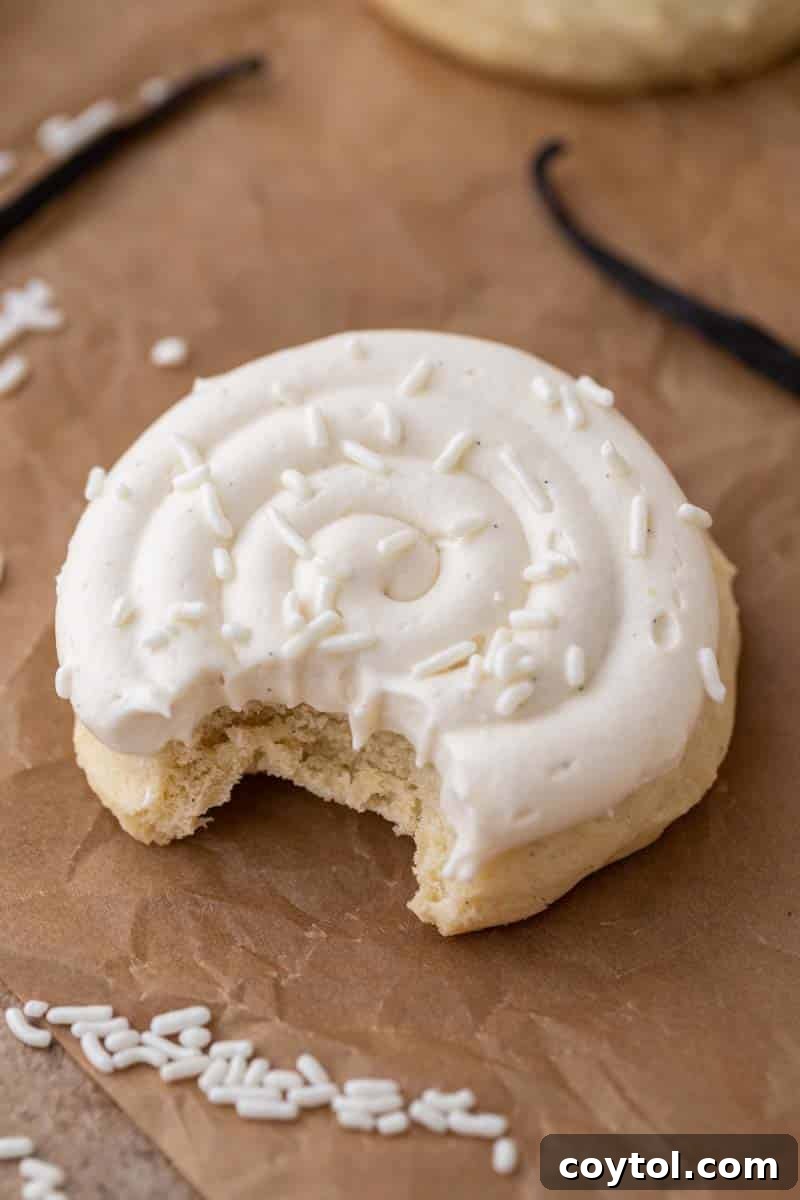 A delectable Crumbl-style Nilla Bean Cupcake Cookie with a bite taken out, revealing its soft vanilla bean interior and whipped buttercream frosting.