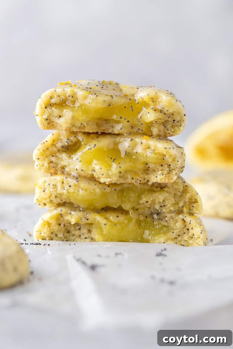 A vibrant stack of Crumbl-style lemon poppy seed cookies, generously stuffed with gooey lemon curd and glazed with zesty icing.