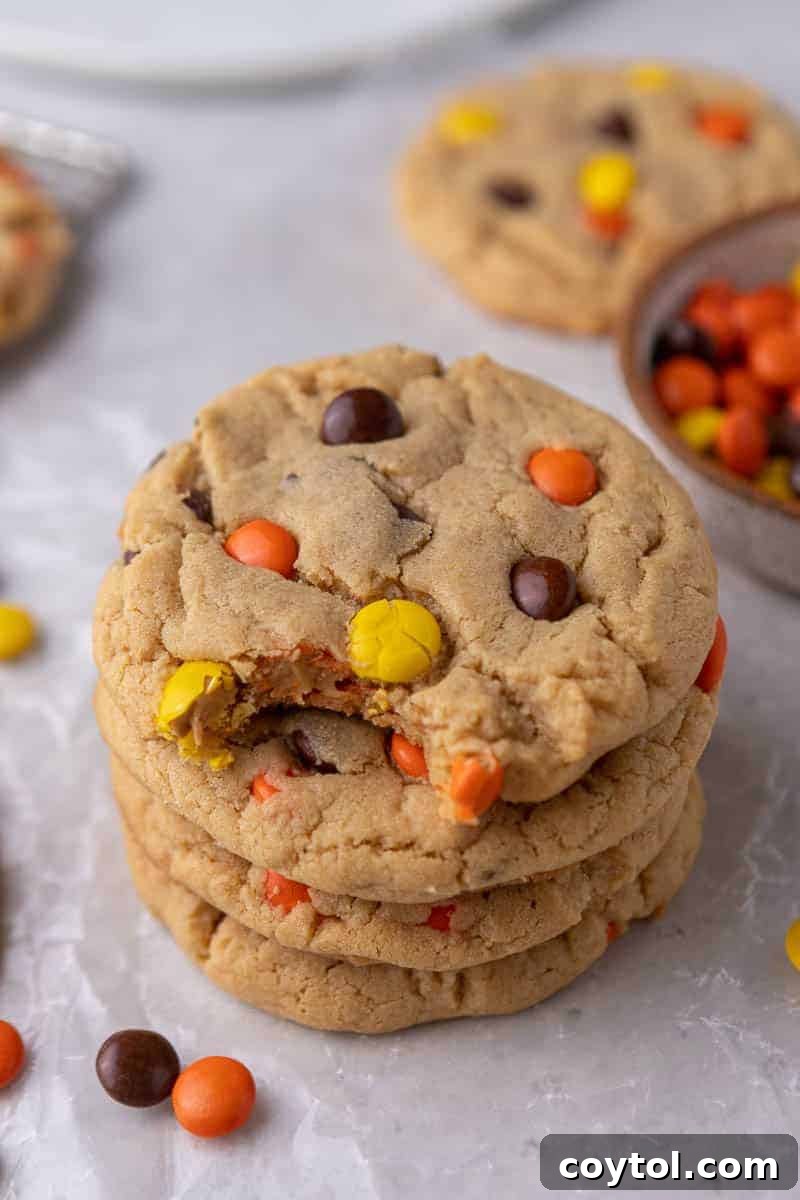 Stacked Crumbl-style Reese's peanut butter cookies, showing their soft, chewy texture and vibrant Reese's Pieces.