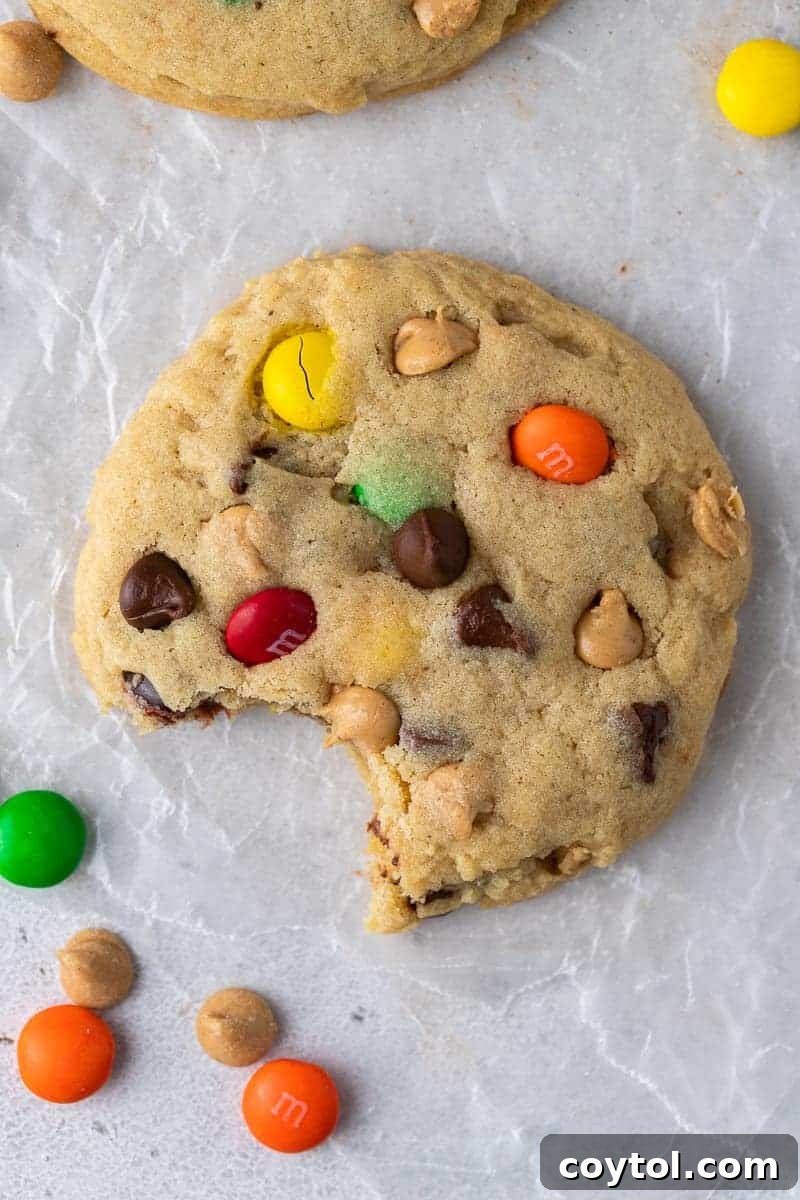 An overhead shot of vibrant Crumbl-style monster cookies, packed with chocolate chips, peanut butter chips, and M&M's.