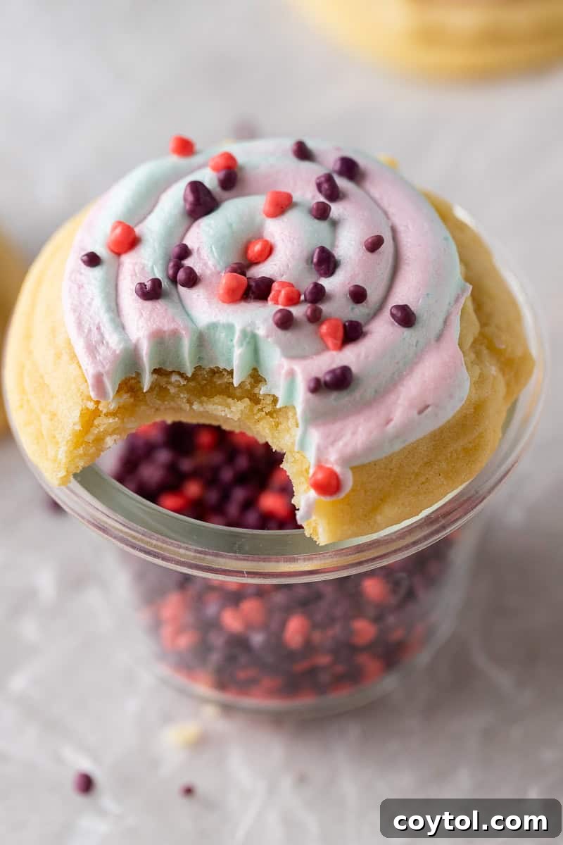 A delightful Crumbl-style Cotton Candy Cookie with a bite taken out, revealing its fluffy cotton-candy frosting and candy crunch.
