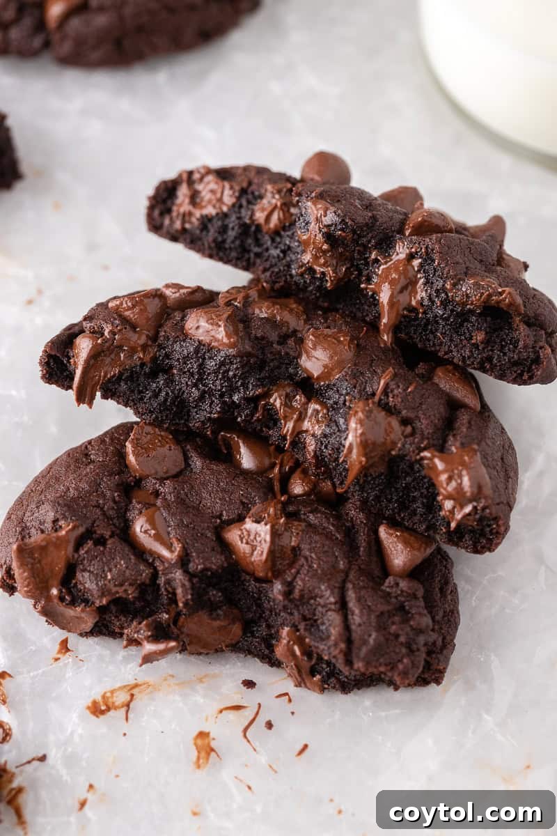 Broken Crumbl-style double chocolate cookies revealing gooey melted chocolate centers, a true delight for chocolate lovers.