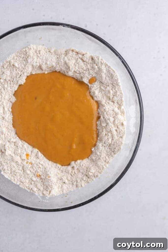 Wet pumpkin mixture added to dry ingredients in a bowl