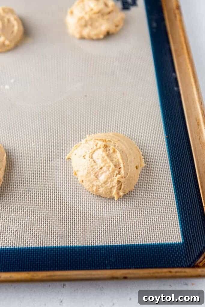 Raw Crumbl banana bread cookie dough portions on a baking sheet before baking.