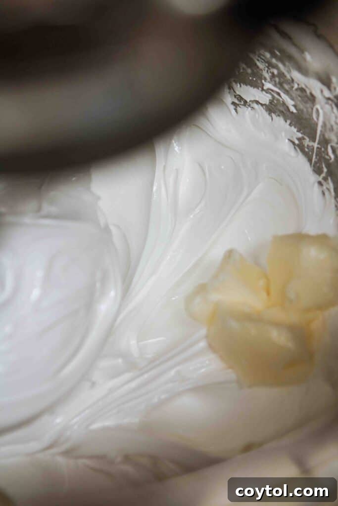 Spooky Black Velvet Monster Cupcakes 12 Adding butter to stiff peak meringue in a stand mixer