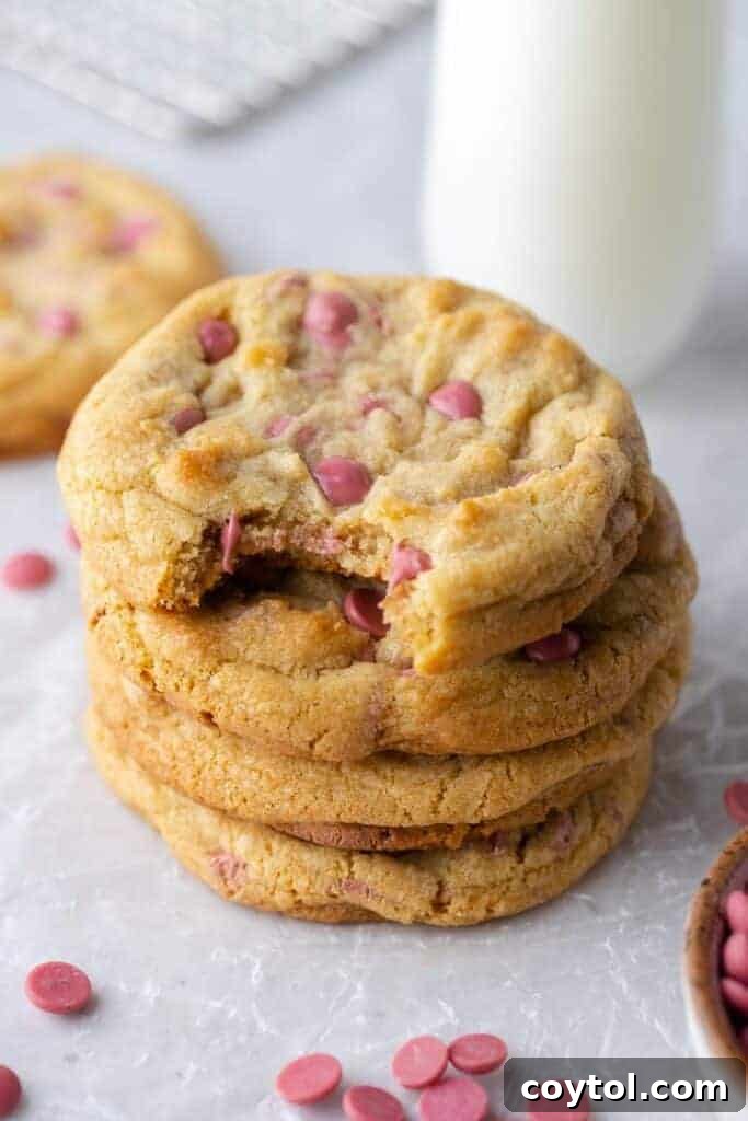 Stack of four thick Crumbl ruby chocolate chip cookies, showing their soft centers