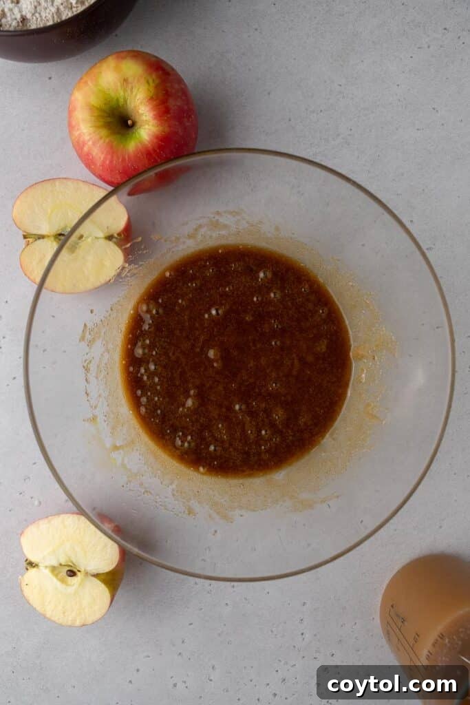 The smoothly combined wet batter mixture, consisting of sugars, oil, and eggs, before the addition of dry ingredients. This showcases the creamy texture and readiness for the next stage of the apple cider bundt cake preparation.