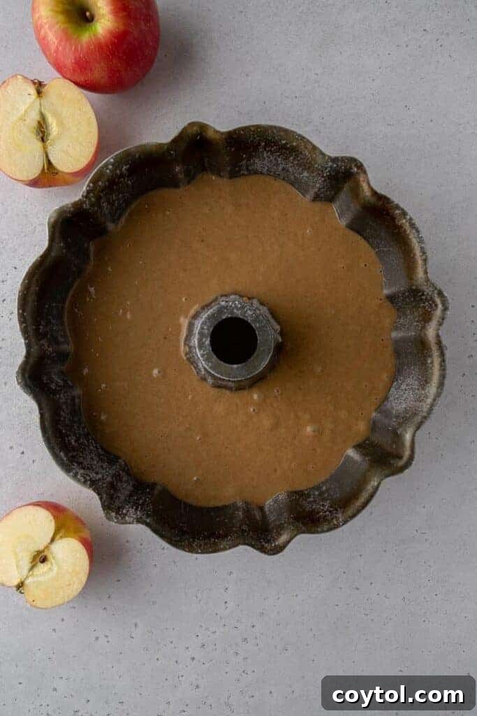 The smooth, spiced apple cider donut bundt cake batter carefully poured into a meticulously greased and floured bundt pan, ready for its transformation in the oven.