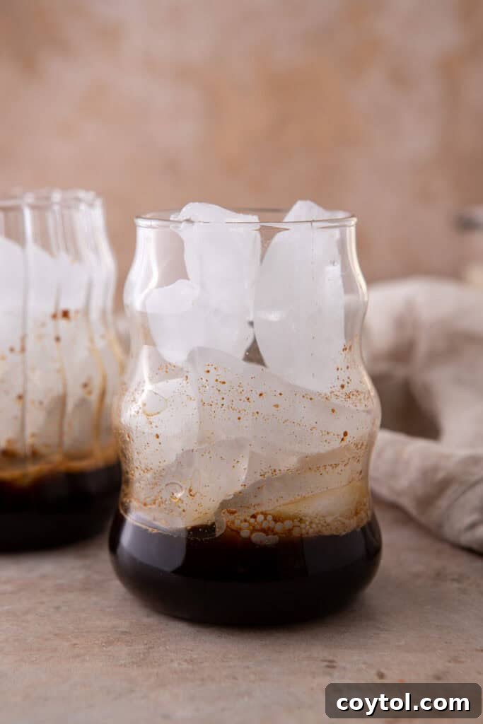 Golden Honey Oat Milk Latte: Hot or Iced 5 Espresso and ice in a glass, showing the base layer for an iced honey oat milk latte.