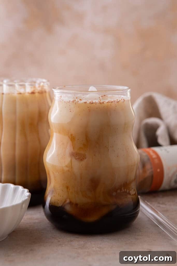 Golden Honey Oat Milk Latte: Hot or Iced 6 Creamy iced honey oat milk latte with espresso and oat milk swirling together.