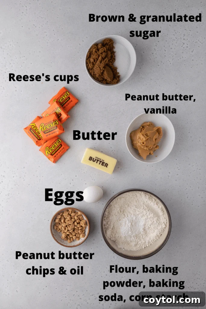 Crumbl Reese's cookie ingredients - a flat lay of butter, peanut butter, sugars, flour, eggs, and Reese's cups on a baking sheet.