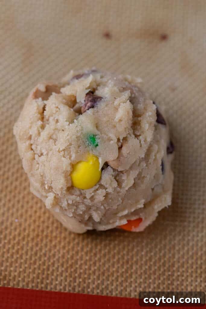 Portioned cookie dough balls, gently flattened, arranged on a baking sheet lined with parchment paper.