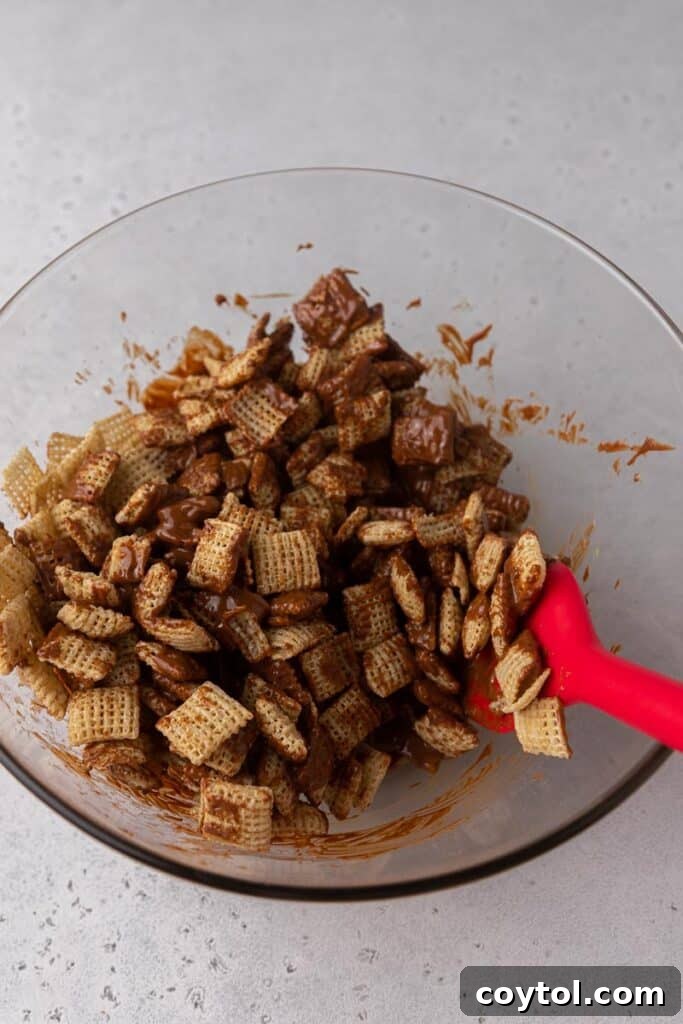 Chex cereal being coated with melted chocolate and peanut butter in a mixing bowl