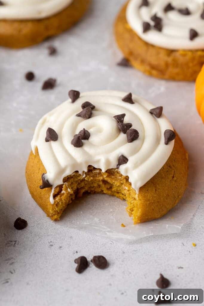 Thick, frosted Crumbl pumpkin cookies with cream cheese frosting and chocolate chips