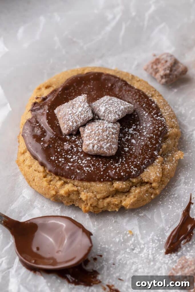 Close-up of a Crumbl Muddy Buddies cookie showing melted chocolate, Chex pieces, and powdered sugar