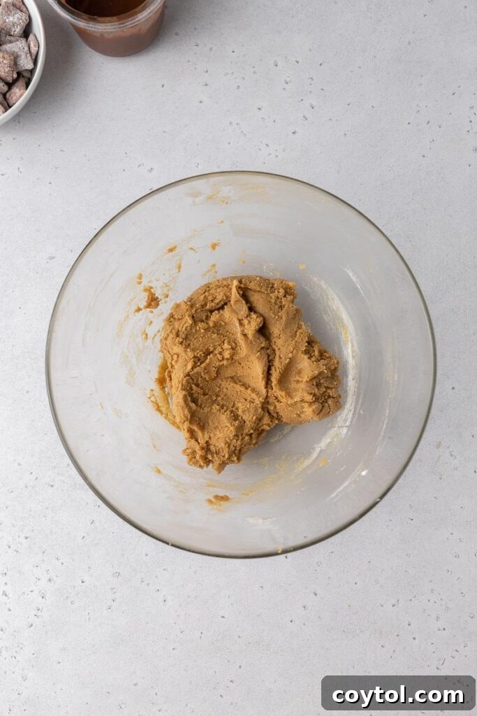 Close-up of peanut butter cookie dough being scooped onto a baking sheet