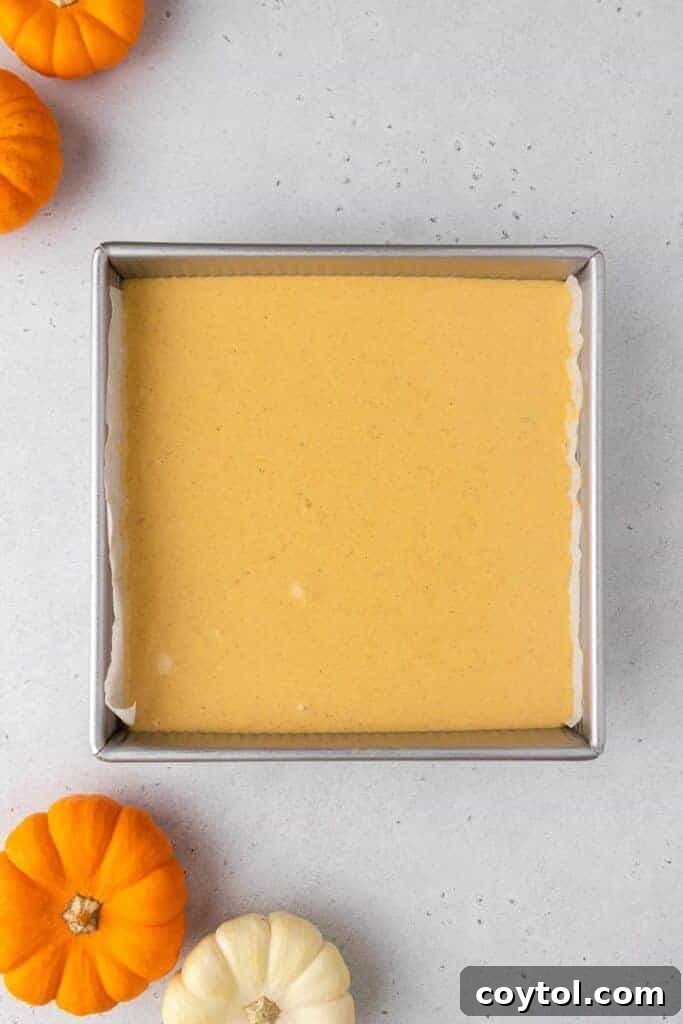 Pumpkin cheesecake batter poured over the graham cracker crust in a baking pan.
