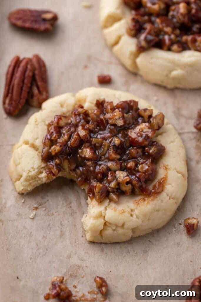 Bakery-Perfect Crumbl Pecan Pie Cookies Homemade 12 Crumbl pecan pie cookie with a bite taken out, showing gooey brown sugar pecan filling over a soft buttery cookie base, highlighting the perfect texture.