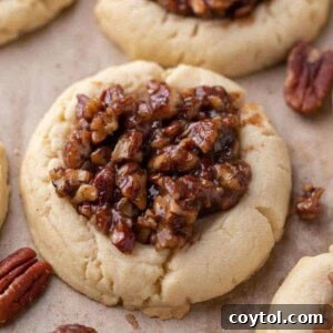 Soft Crumbl pecan pie cookies topped with gooey pecan filling on parchment paper
