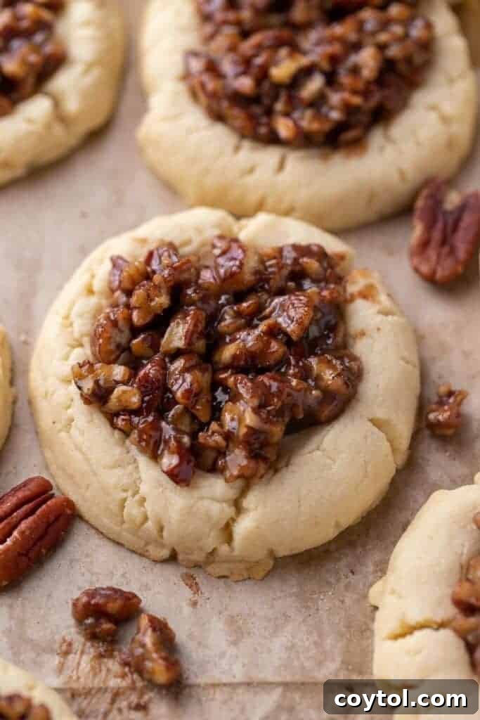 Bakery-Perfect Crumbl Pecan Pie Cookies Homemade 4 Soft Crumbl pecan pie cookies topped with gooey pecan filling on parchment paper