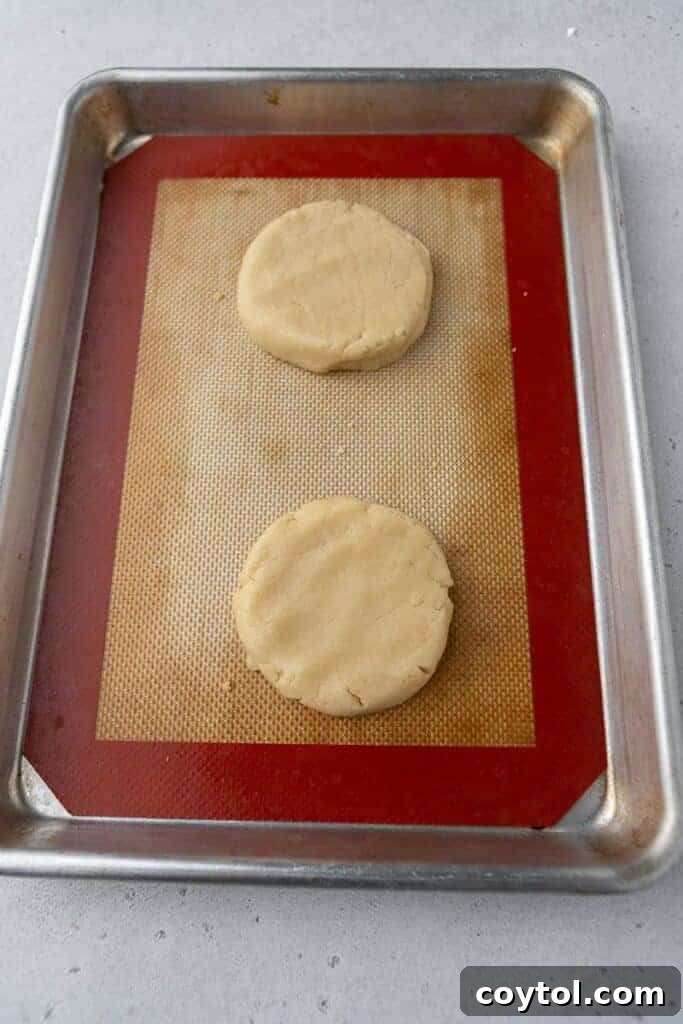 Bakery-Perfect Crumbl Pecan Pie Cookies Homemade 6 Flattened cookie dough discs on a lined baking sheet before shaping, showing even spacing.