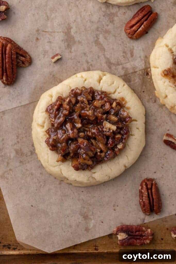 Bakery-Perfect Crumbl Pecan Pie Cookies Homemade 10 Overhead shot of Crumbl pecan pie cookie with glossy pecan topping and scattered pecans, highlighting the finished product.