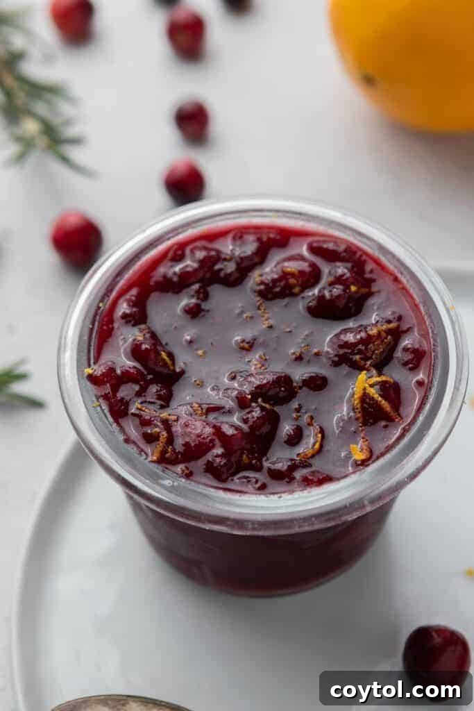 Homemade cranberry sauce with oranges in a glass bowl, garnished with orange slices.