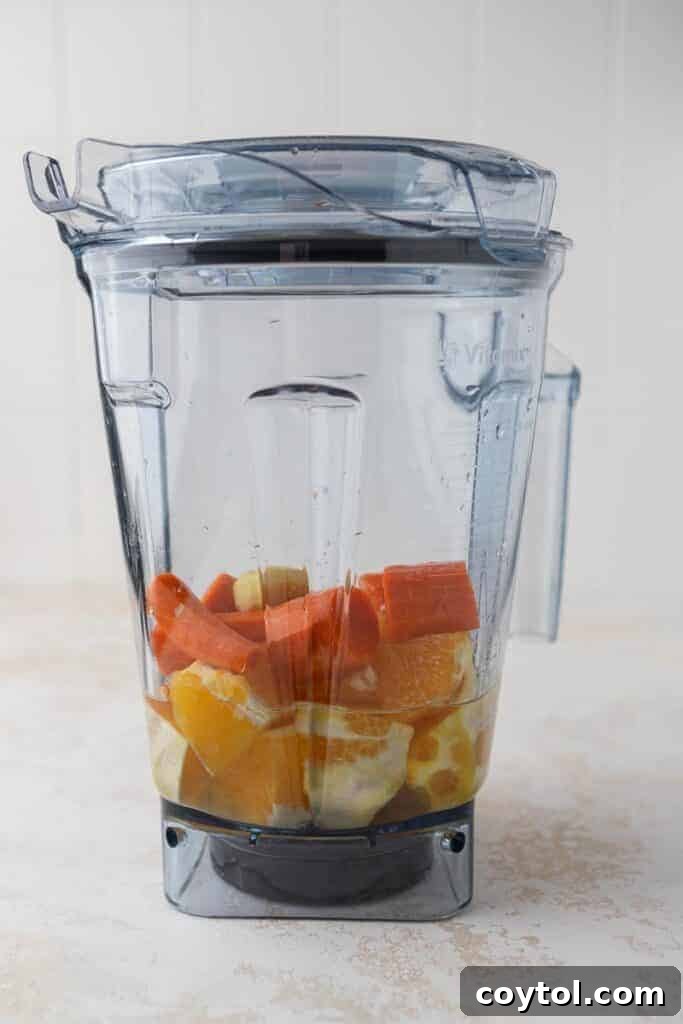 Golden Glow Immune Support Smoothie 4 Fresh oranges, carrots, and ginger being added to a Vitamix blender, ready for blending.