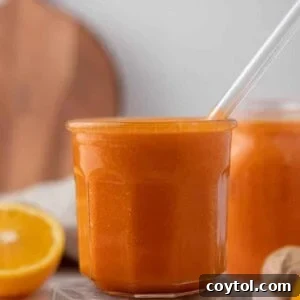 A bright orange smoothie in a glass, ready for enjoyment.