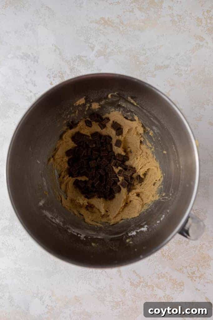 Delightful Mini Crumbl Chocolate Chip Cookie Cups 5 Chocolate chip cookie dough with visible semi-sweet chocolate chunks in a mixing bowl, after all ingredients have been combined.