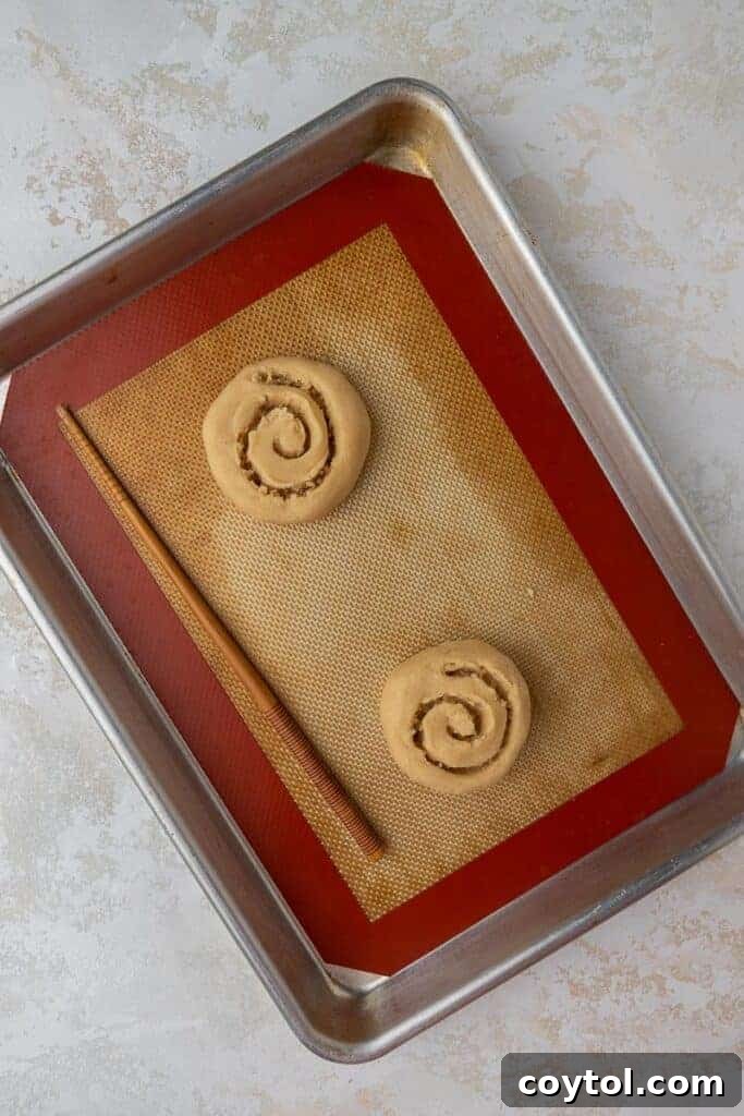 Crumbl Honey Bun Cookies: Sweet Perfection 13 Close-up demonstrating how to create honey bun swirls on cookies with a chopstick.