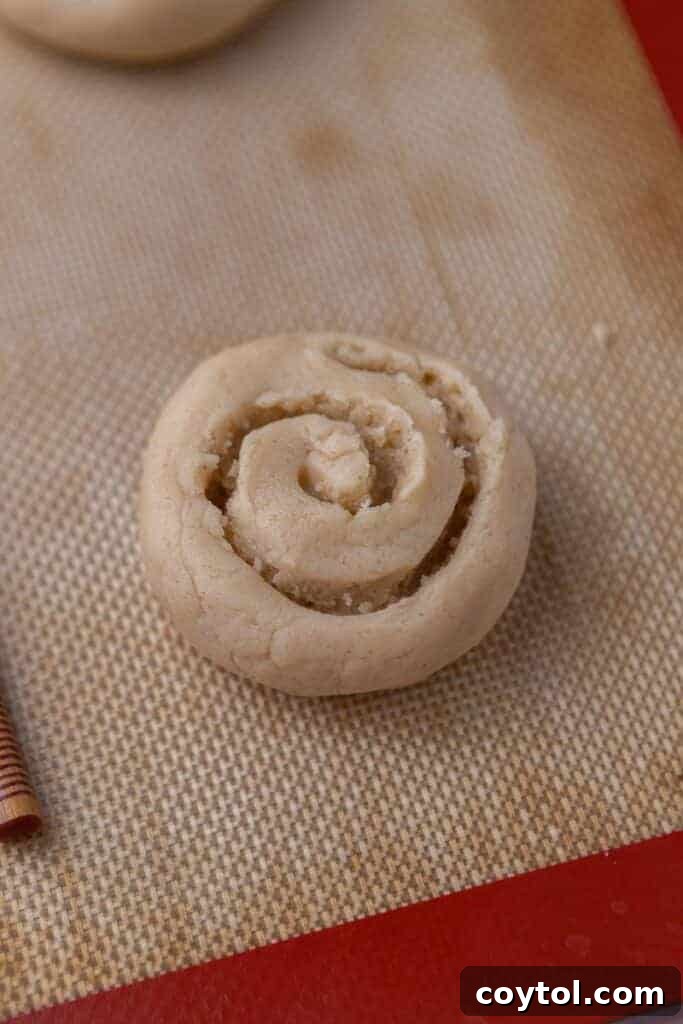 Crumbl Honey Bun Cookies: Sweet Perfection 7 Cookie dough balls on baking sheet, ready for the swirl indentations.