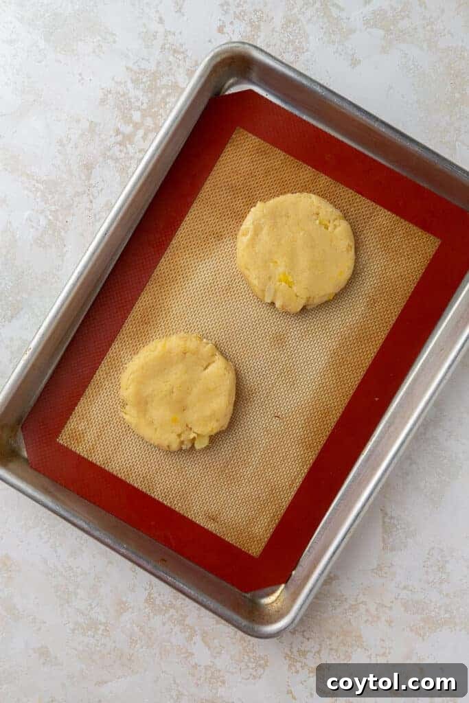Pineapple cookie dough balls flattened on baking sheet