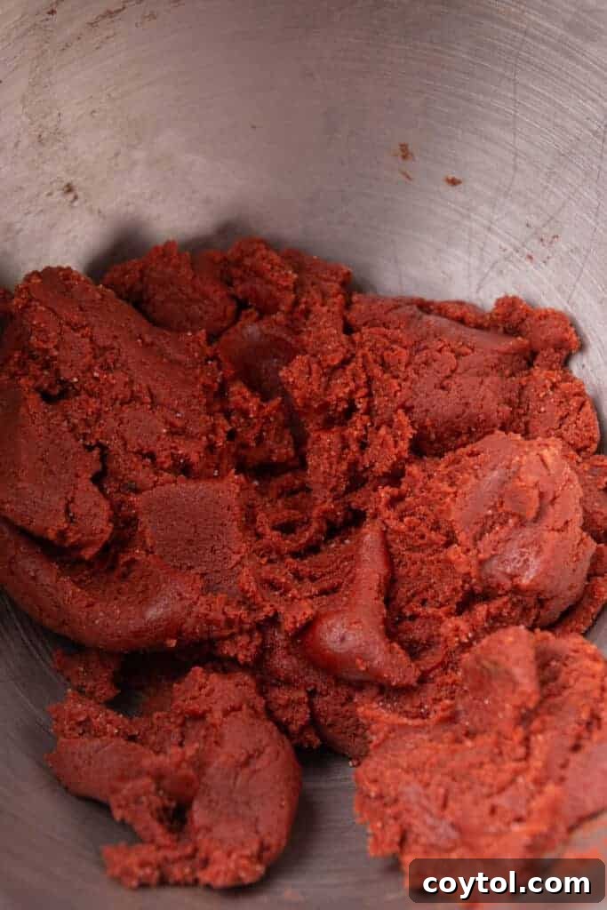 Vibrant red velvet cookie dough in mixing bowl after adding food coloring