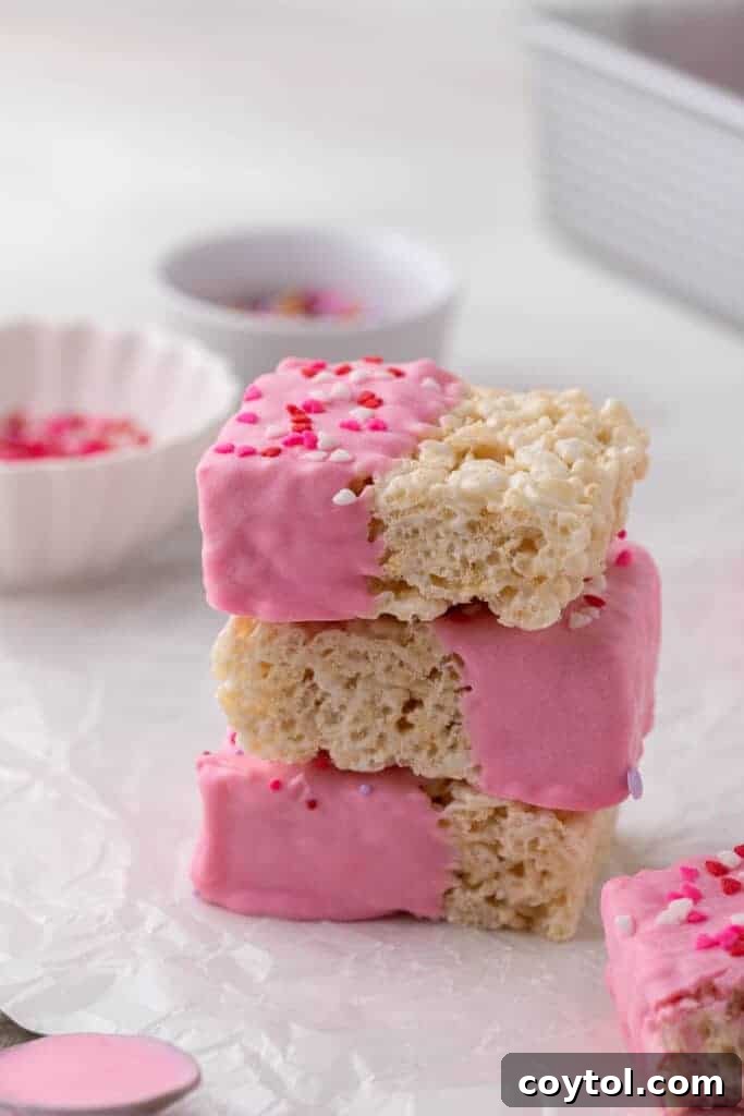 Stack of Chocolate covered Rice Krispie treats, dipped in pink candy melt and adorned with Valentine's Day sprinkles.