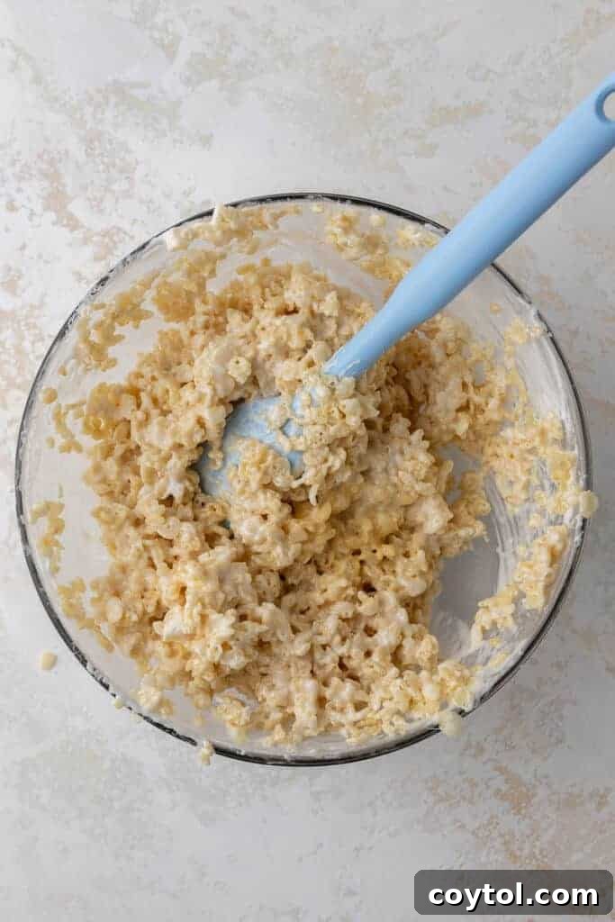 Rice Krispie treat mixture being stirred in a bowl.