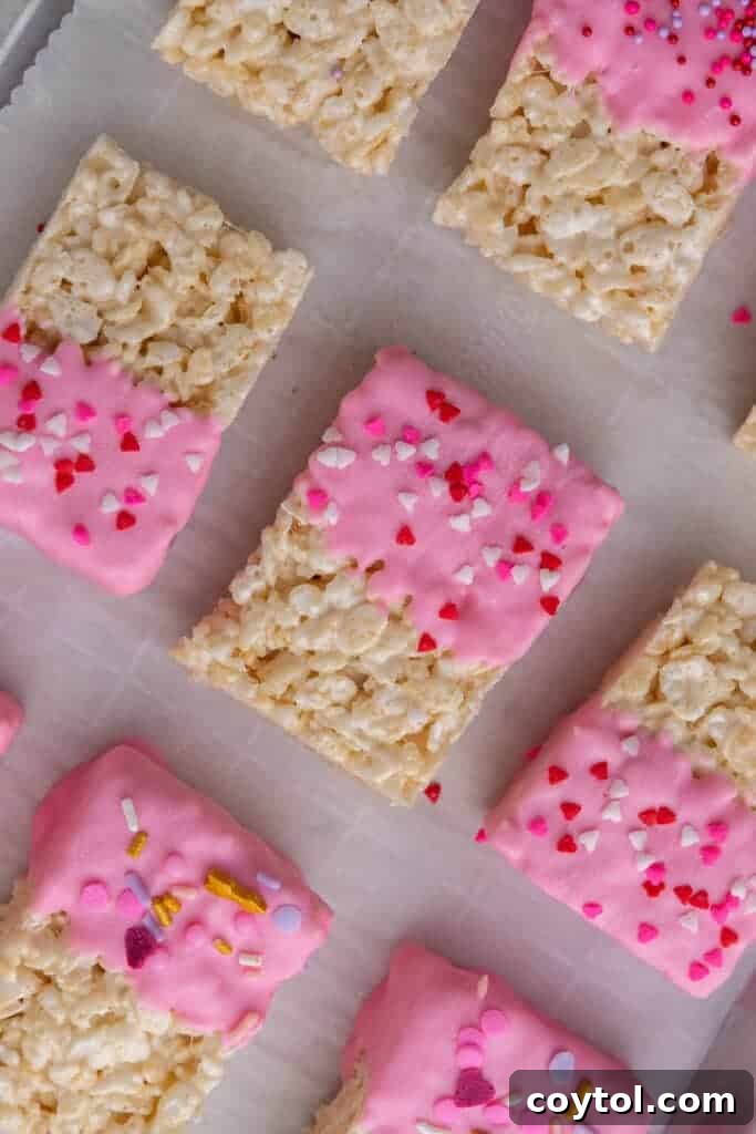 Valentine's day Rice Krispie treats being decorated with sprinkles.