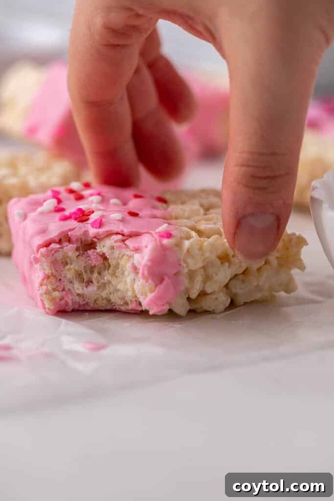 Hand grabbing a chocolate covered rice krispie treat from a festive display.